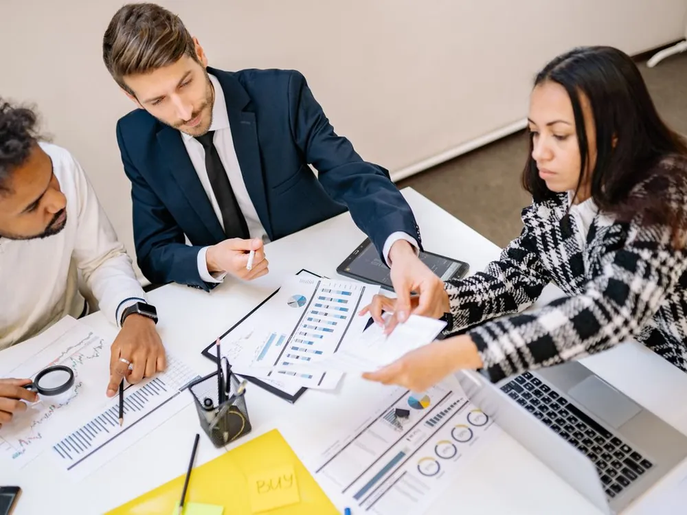 Overhead view of a team comparing charts and documents on a desk