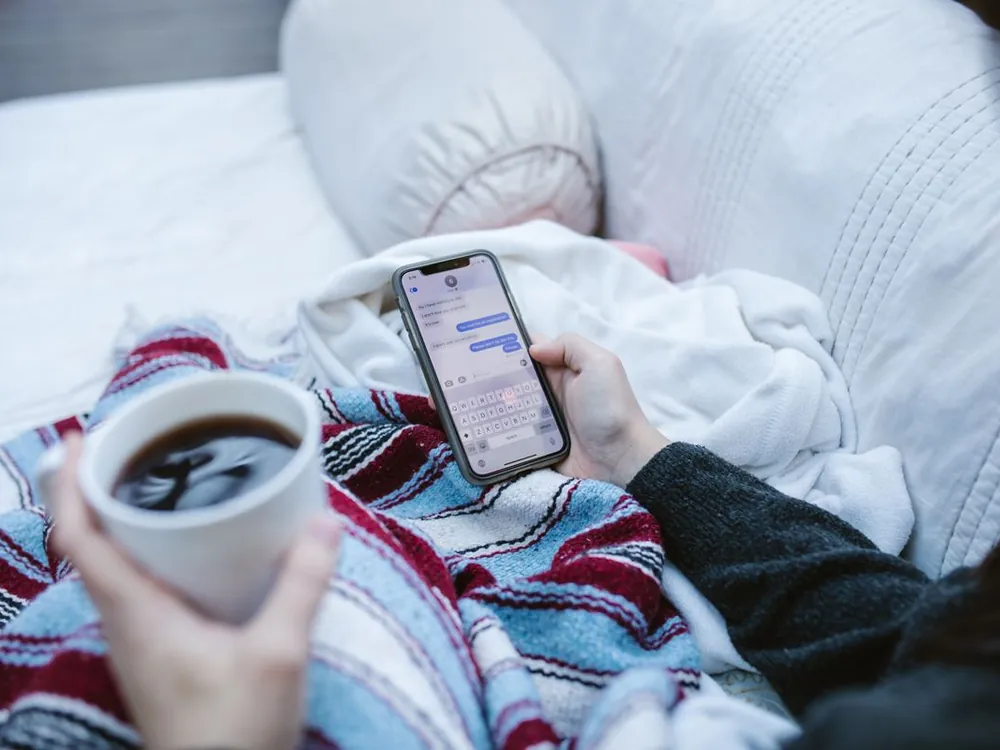 Person messaging on a phone with a cup of coffee