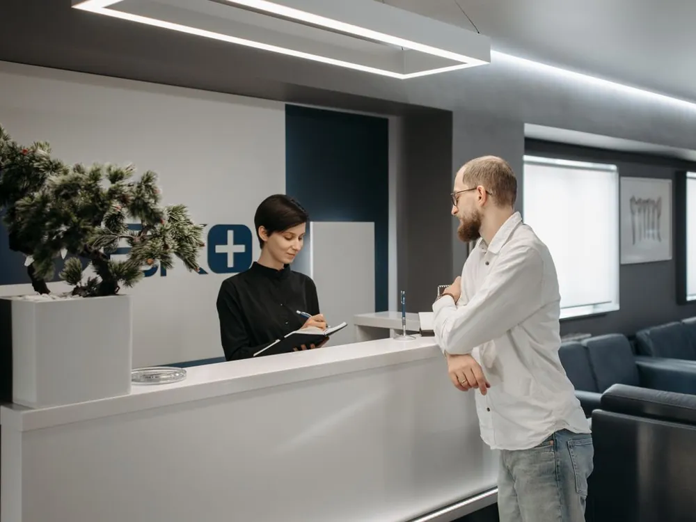 A receptionist greeting a visitor at a modern front desk