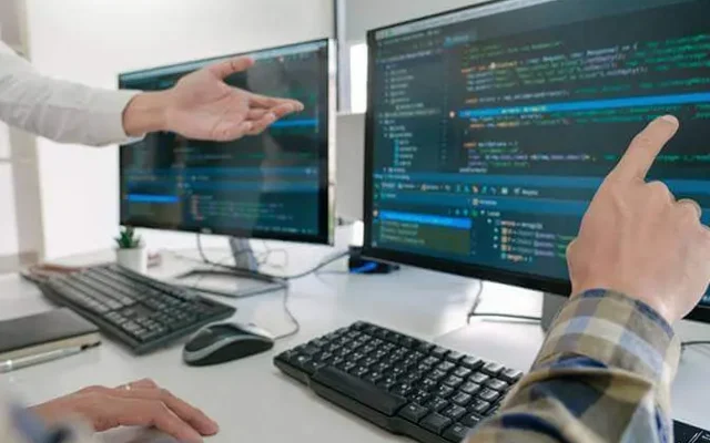 Colleagues reviewing software on two monitors