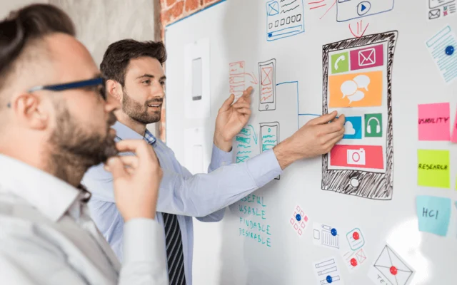 Colleagues mapping a workflow with notes on a wall
