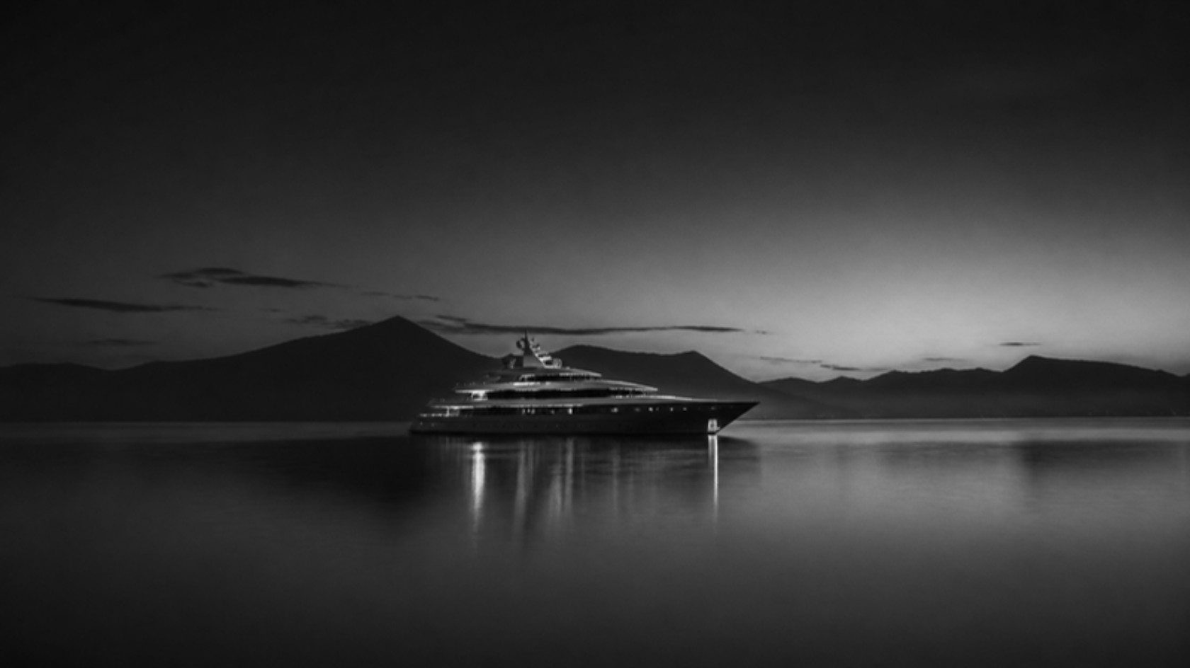 A private yacht at anchor in a still bay at dusk